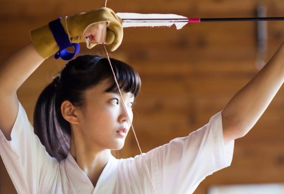 A young woman drawing a bow and taking aim